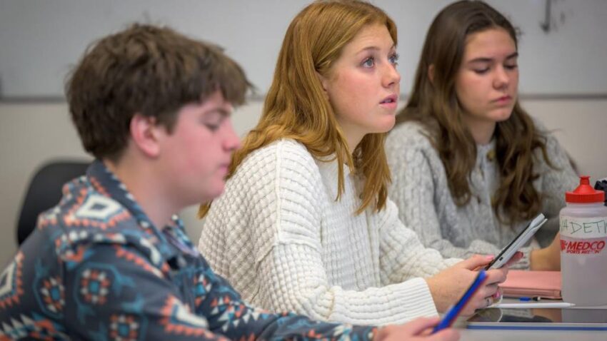 A high school student highlighting key phrases in a nonfiction excerpt during AP Lang study session.